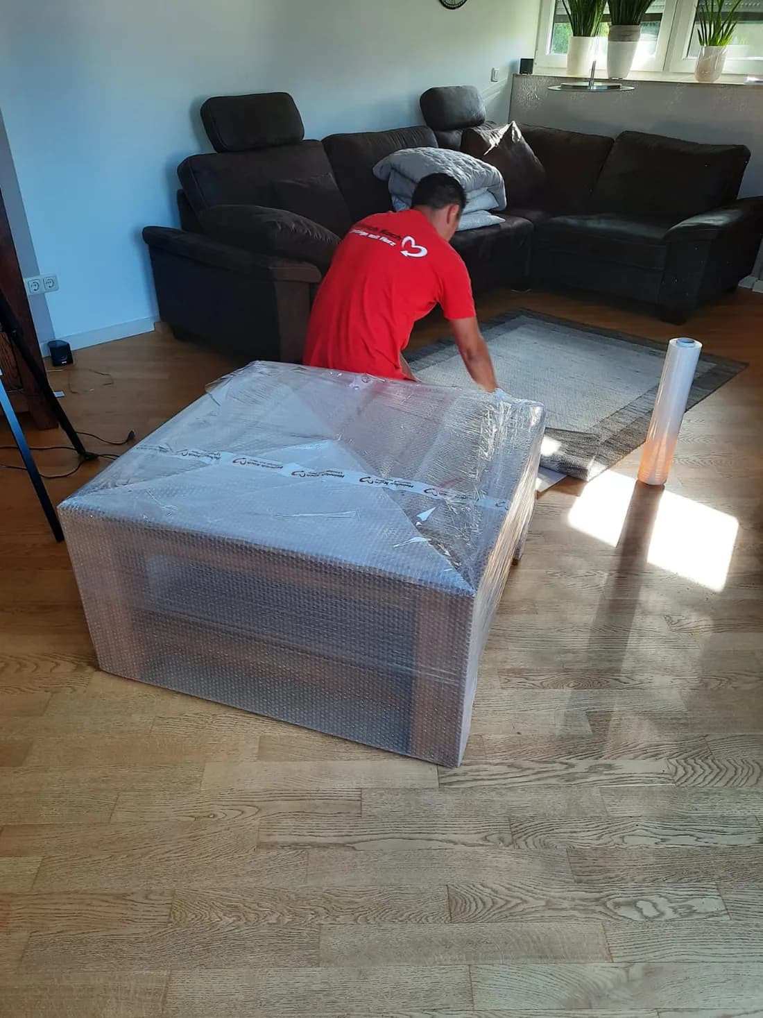 Koch Möbelpacker verpackt Möbel sorgfältig im Wohnzimmer des Kunden